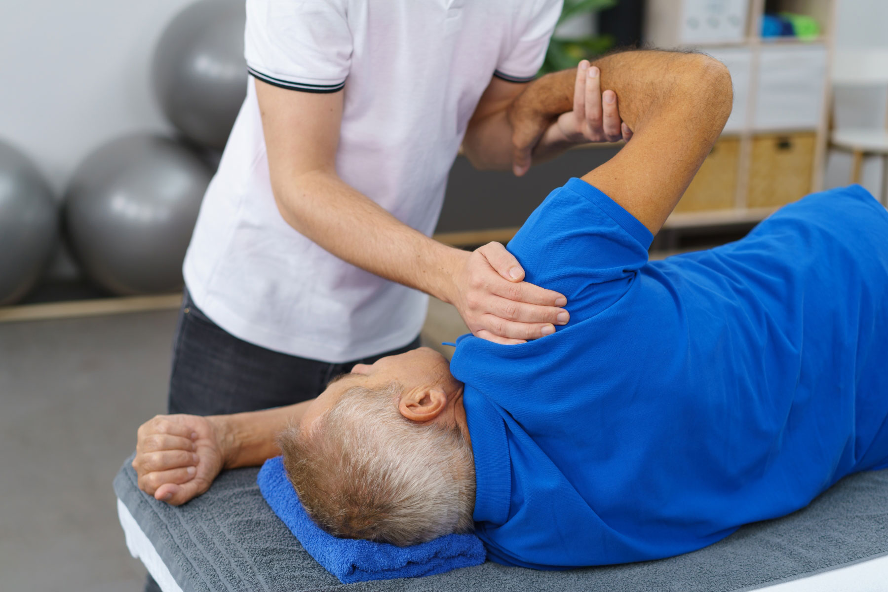 En fysioterapeut eller manuellterapeut jobber med skulderen til en pasient. Illustrasjonsfoto: Mostphotos