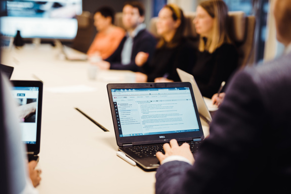 Flere personer sitter rundt et bord, Lovdata vises på en PC-skjerm. Foto: Cecilie Bannow.