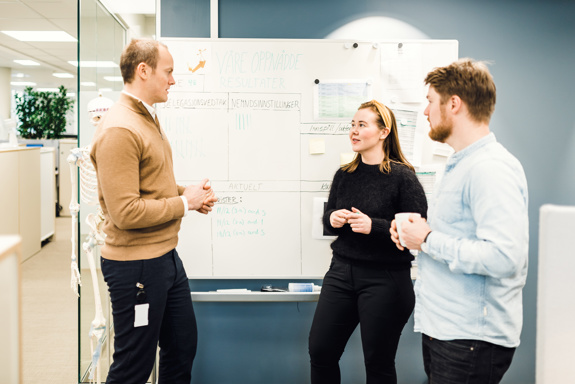 Tre personer står foran en tavle og diskuterer. Foto: Cecilie Bannow.