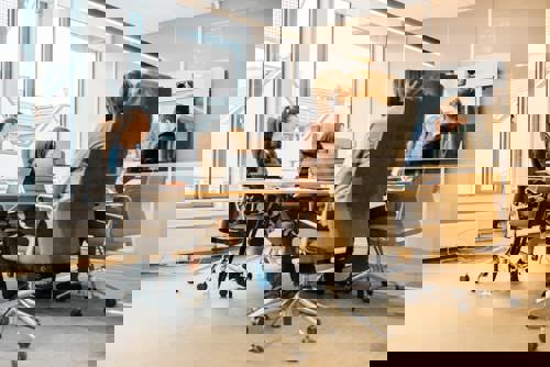 Bilde av personer rundt et bord med datamaskiner på et møterom. Foto: Cecilie Bannow.