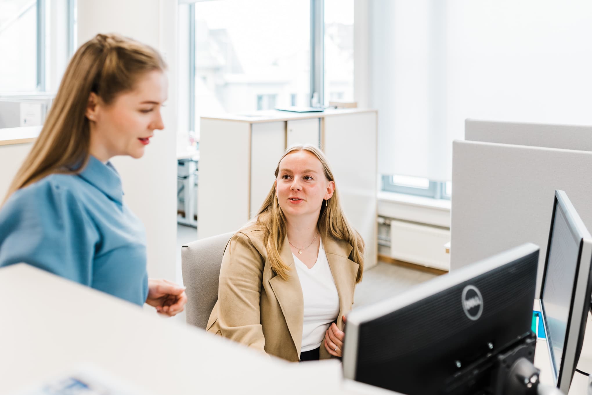 Ei kvinne sit ved ein pc. Ei anna kvinne står ved sidan av og ser ned på pc-en. Foto: Cecilie Bannow.