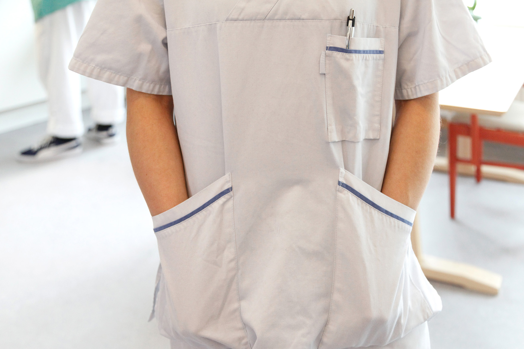 Helsepersonell med hendene i lommen på arbeidsuniformen. Foto: Mostphotos.