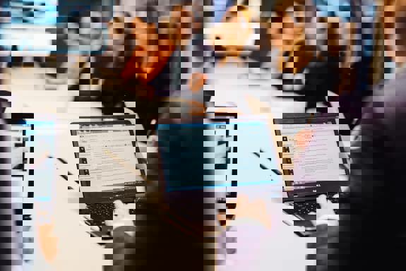 Flere personer sitter rundt et bord. På bordet er det PC-er og papirer. Foto: Cecilie Bannow.