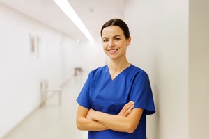 En lege står i en sykehuskorridor. Hun ser rett på oss og smiler. Foto: Mostphotos.